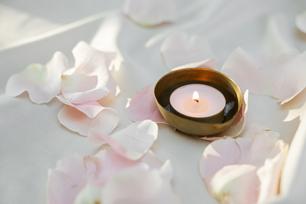 Close-Up Photo of a Lit Candle Near Flower Petals